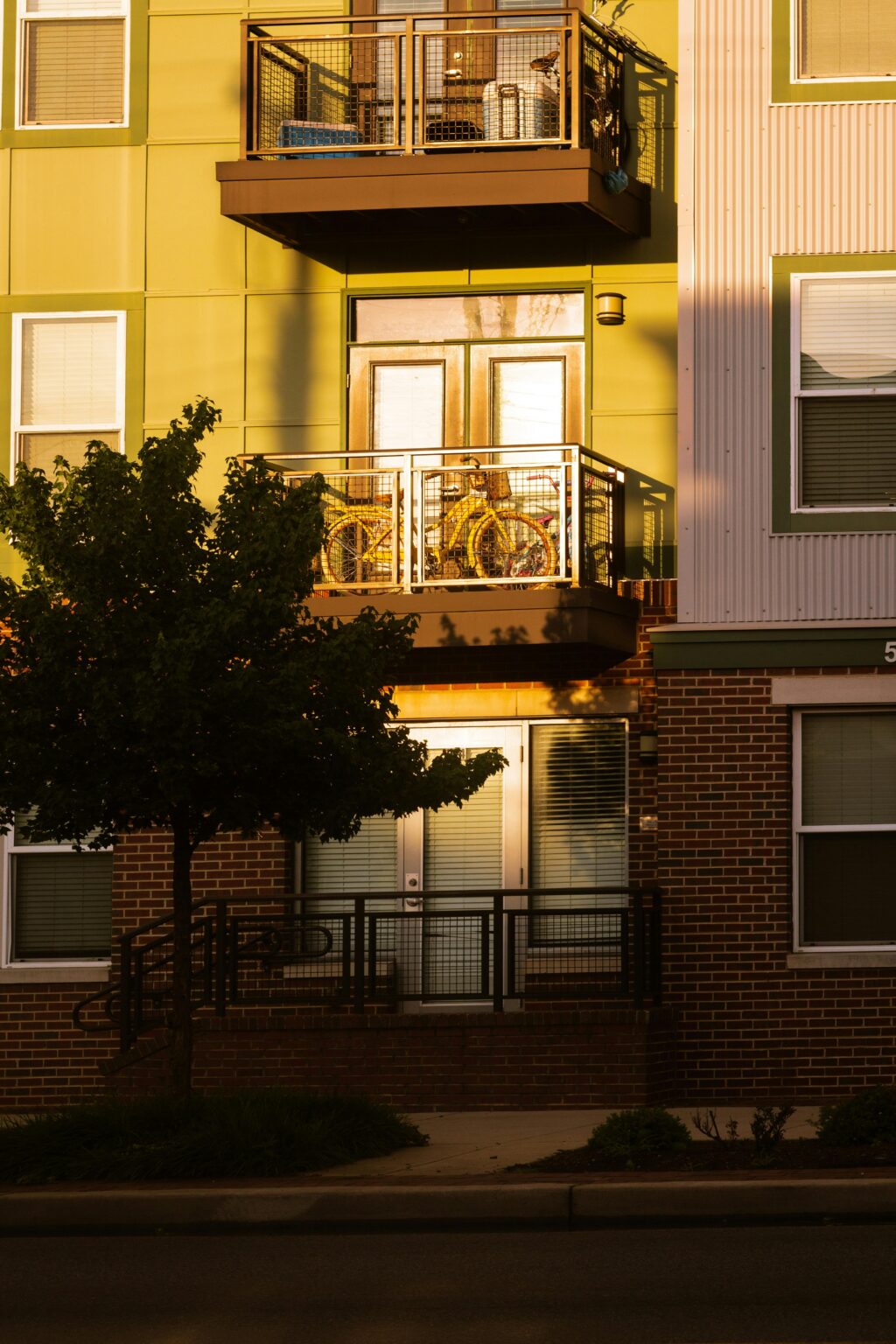 A contemporary urban apartment exterior featuring a balcony with a bicycle during golden hour.