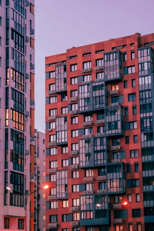 Contemporary high-rise apartment buildings in city during sunrise, showcasing modern architectural design.